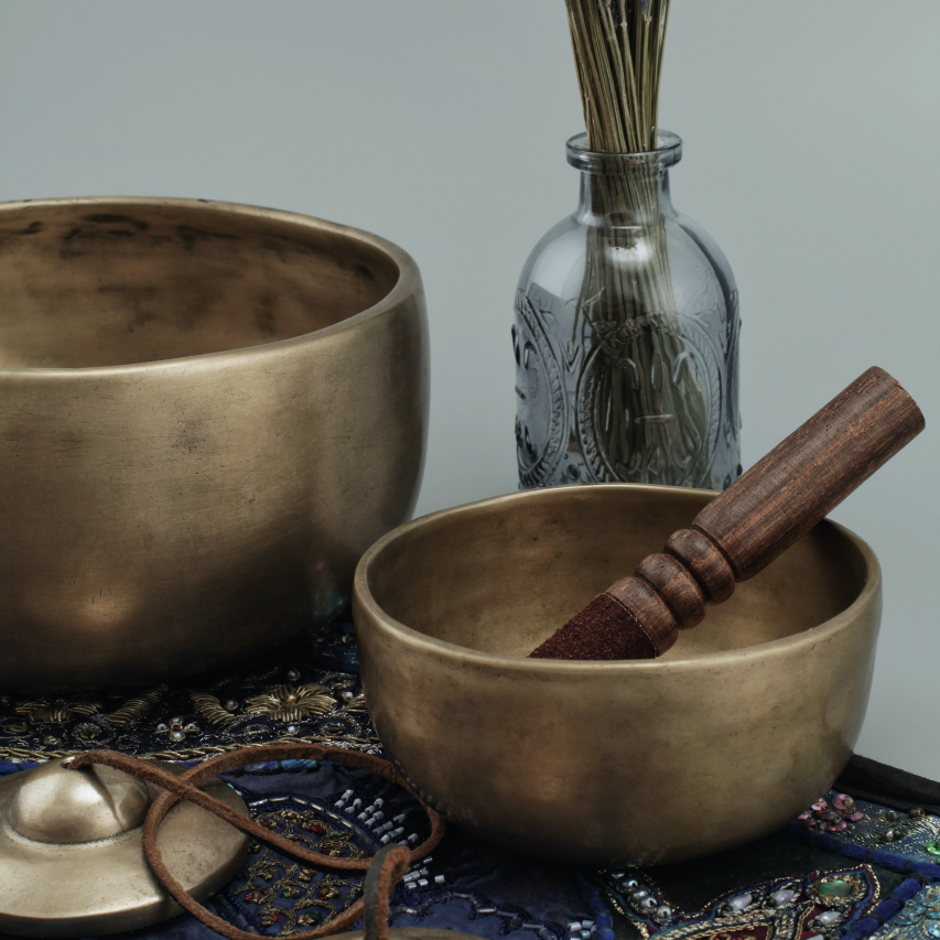 Cuencos de sonido, talismán y aromaterapia en una mesa pequeña.